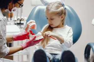 Una dentista spiega a una bambina come lavare i denti