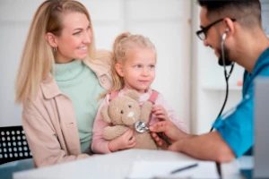 Medico con casacca che interagisce con una bambina e il genitore